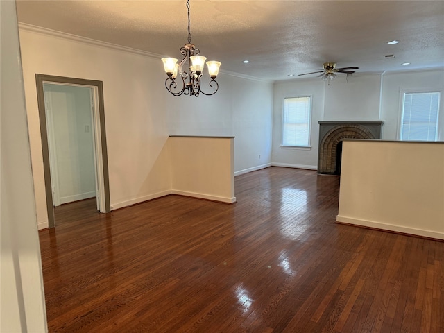 interior space with a brick fireplace, ceiling fan with notable chandelier, dark hardwood / wood-style flooring, a textured ceiling, and ornamental molding