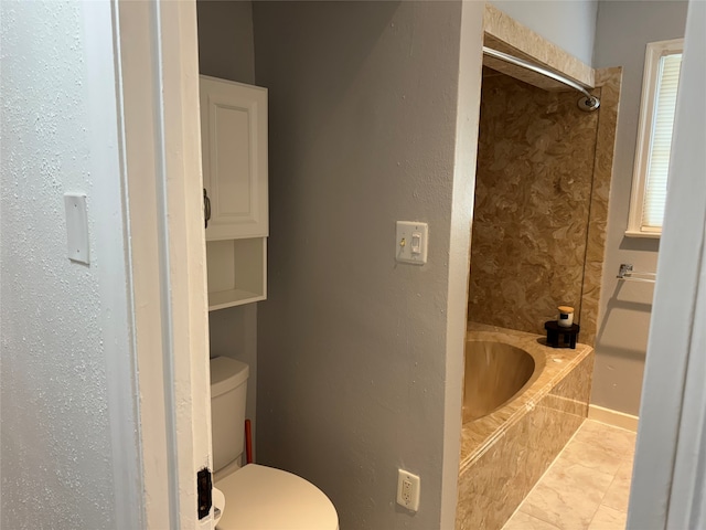 bathroom with toilet, tile patterned floors, and tiled shower / bath