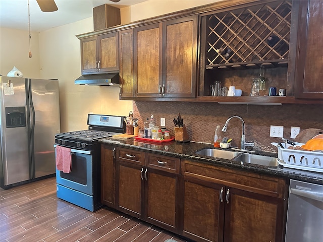 kitchen featuring ceiling fan, sink, dark wood-type flooring, stainless steel appliances, and dark stone countertops