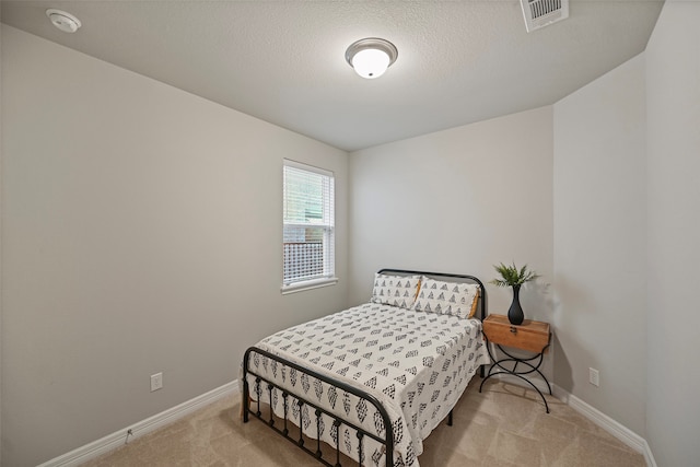 bedroom featuring a textured ceiling and light carpet