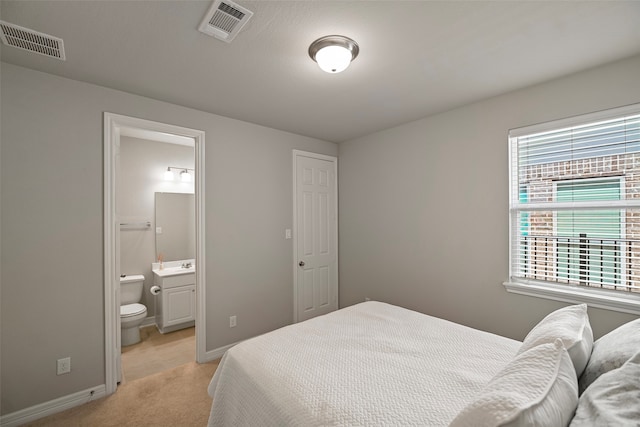 carpeted bedroom with ensuite bath and sink