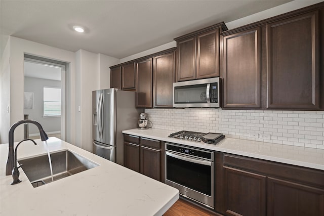 kitchen featuring dark brown cabinetry, stainless steel appliances, light wood-type flooring, and sink