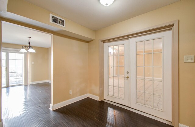 foyer entrance featuring dark wood-type flooring, french doors, and a notable chandelier