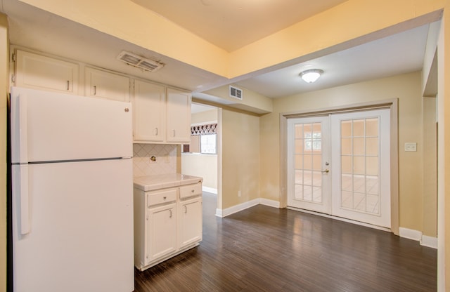 kitchen with dark wood-type flooring, white cabinets, white fridge, backsplash, and french doors