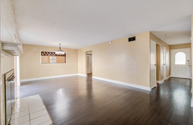 unfurnished living room featuring an inviting chandelier and dark wood-type flooring