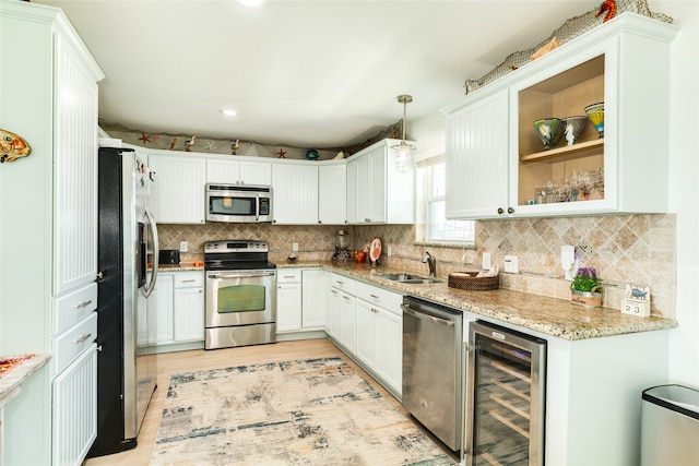 kitchen with pendant lighting, wine cooler, white cabinets, sink, and appliances with stainless steel finishes