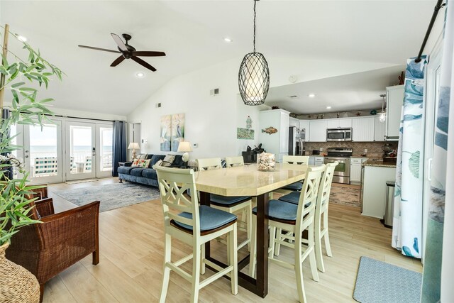 dining space featuring light hardwood / wood-style floors, ceiling fan, french doors, and high vaulted ceiling