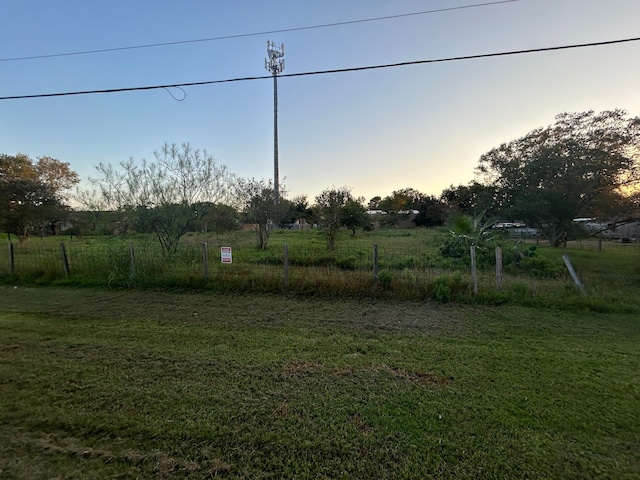 yard at dusk featuring a rural view