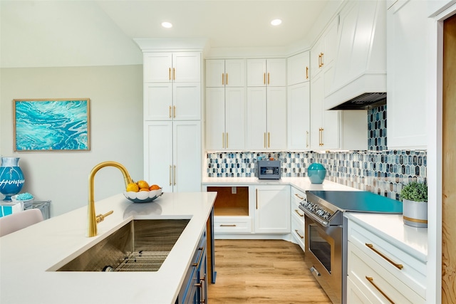 kitchen with white cabinets, light hardwood / wood-style flooring, sink, high end stainless steel range, and premium range hood