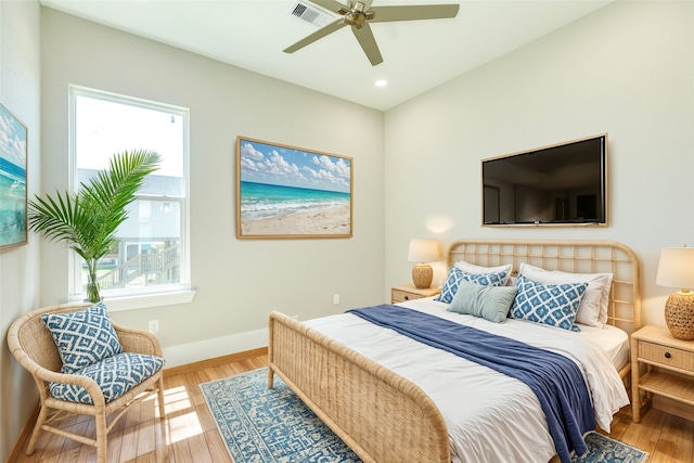 bedroom featuring hardwood / wood-style floors, ceiling fan, and multiple windows