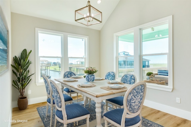 dining area featuring vaulted ceiling, a notable chandelier, and light hardwood / wood-style flooring