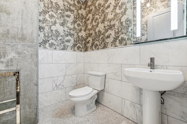 bathroom featuring toilet, tile patterned flooring, and tile walls