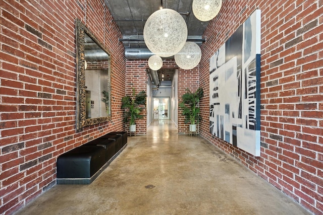 corridor with brick wall, concrete flooring, and a high ceiling