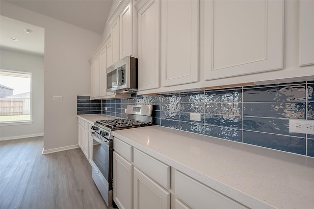 910 Rosewood Trl, Beasley, TX 77417 - kitchen with light countertops, white cabinets, stainless steel appliances, light wood-style floors, and backsplash