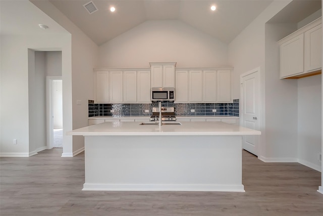 910 Rosewood Trl, Beasley, TX 77417 - kitchen with light countertops, visible vents, stainless steel microwave, a center island with sink, and backsplash