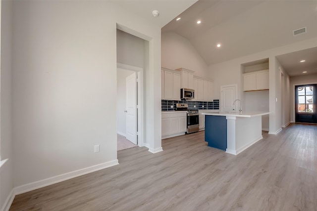 910 Rosewood Trl, Beasley, TX 77417 - kitchen featuring decorative backsplash, white cabinets, visible vents, light wood finished floors, and appliances with stainless steel finishes