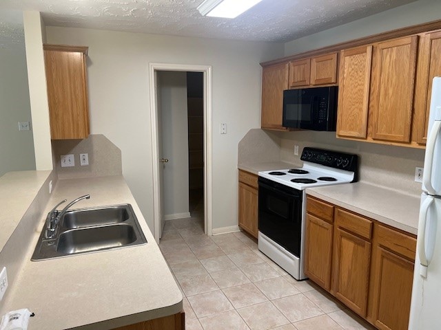 kitchen with a textured ceiling, white appliances, sink, and light tile patterned floors