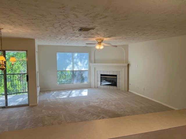 unfurnished living room with carpet, ceiling fan, a tile fireplace, and a textured ceiling