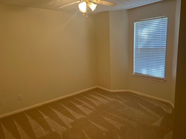 carpeted spare room with ceiling fan and a textured ceiling