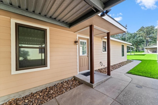 entrance to property featuring a yard and a patio area