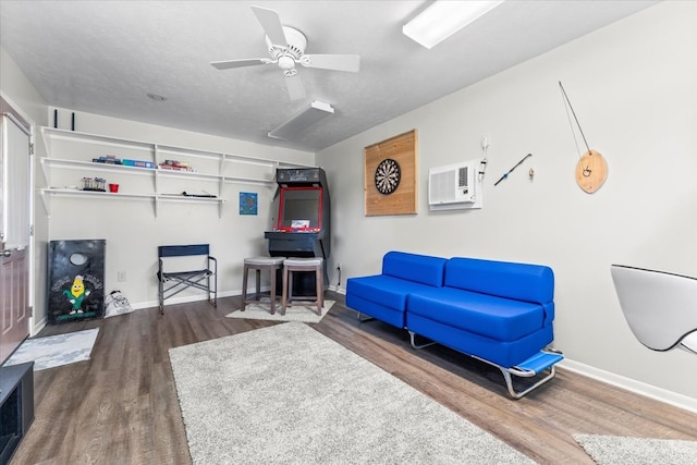 living room featuring a textured ceiling, an AC wall unit, ceiling fan, and hardwood / wood-style flooring