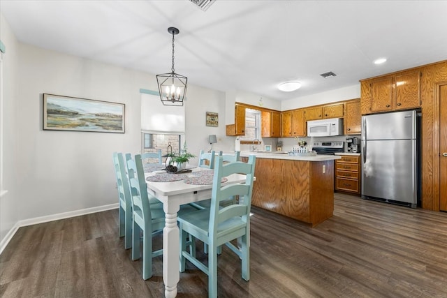 kitchen featuring appliances with stainless steel finishes, dark hardwood / wood-style flooring, pendant lighting, sink, and a chandelier