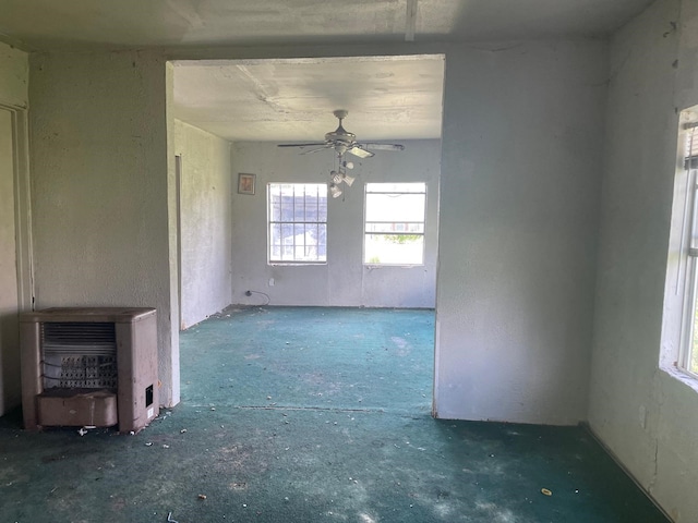 unfurnished living room featuring ceiling fan and heating unit