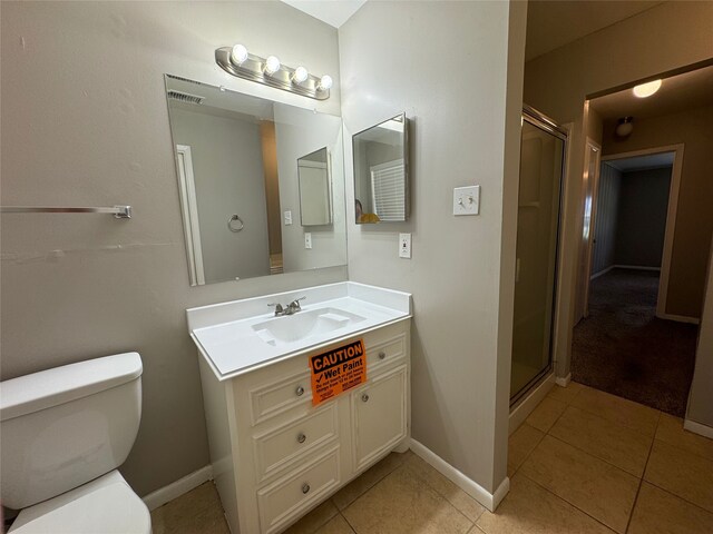 bathroom with tile patterned flooring, walk in shower, vanity, and toilet