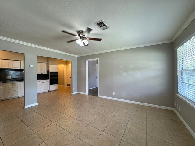 unfurnished living room featuring ceiling fan, ornamental molding, and light tile patterned floors