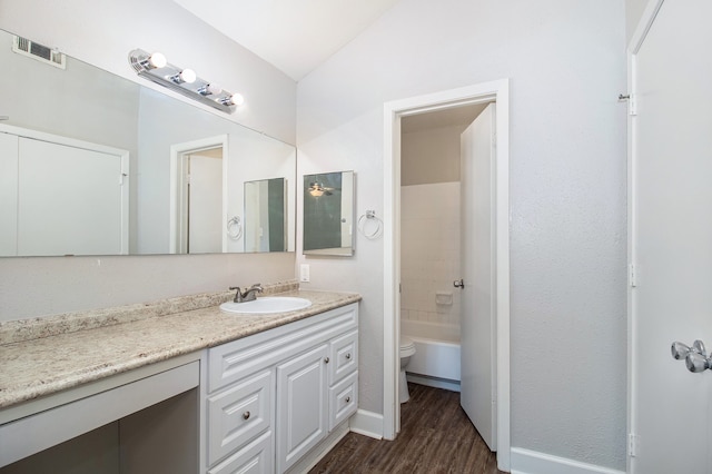 bathroom featuring wood-type flooring, vanity, toilet, and vaulted ceiling