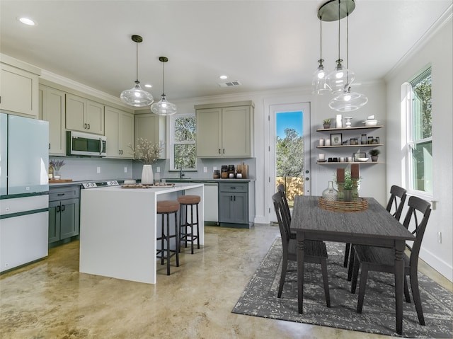 kitchen with hanging light fixtures, a kitchen bar, white appliances, and a center island