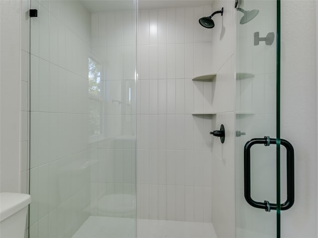 bathroom with a shower with door and toilet