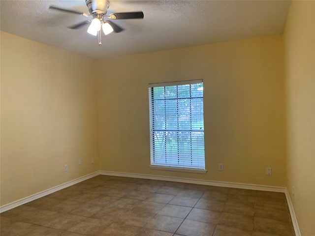 tiled spare room with a textured ceiling and ceiling fan