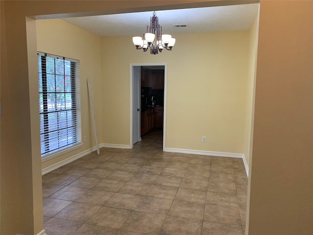 empty room with an inviting chandelier and light tile patterned floors