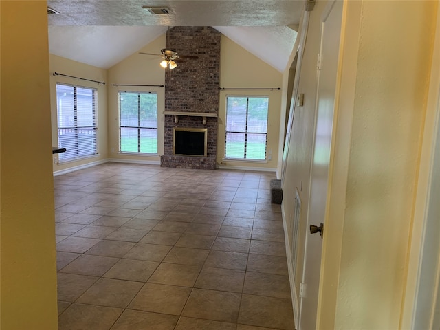 unfurnished living room with a brick fireplace, tile patterned flooring, ceiling fan, and a textured ceiling