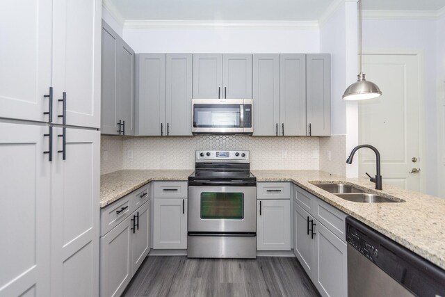 kitchen featuring hanging light fixtures, light stone counters, gray cabinets, stainless steel appliances, and sink