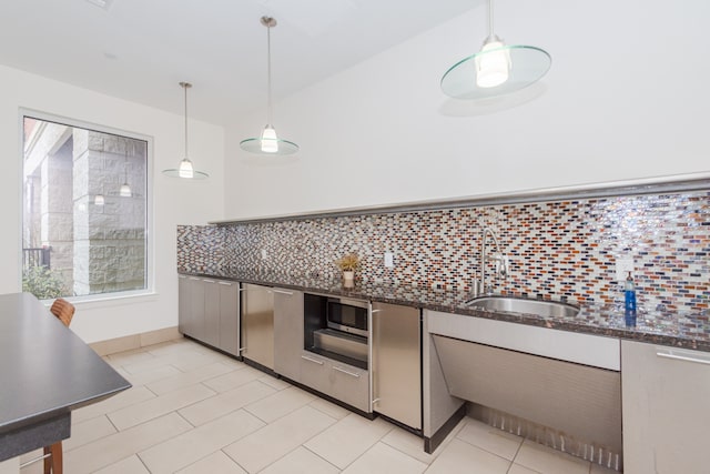 kitchen with backsplash, dark stone countertops, sink, and pendant lighting