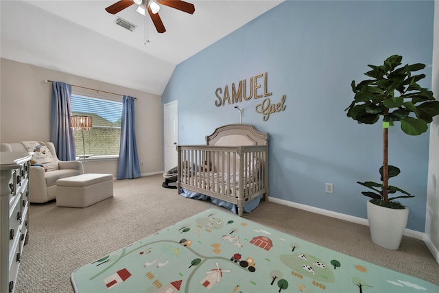 carpeted bedroom with a crib, lofted ceiling, and ceiling fan