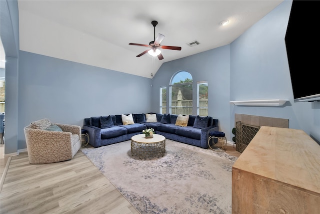 living room with ceiling fan, a fireplace, light wood-type flooring, and lofted ceiling