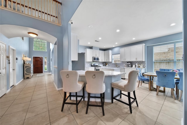 kitchen featuring white cabinets, light stone counters, appliances with stainless steel finishes, and a healthy amount of sunlight