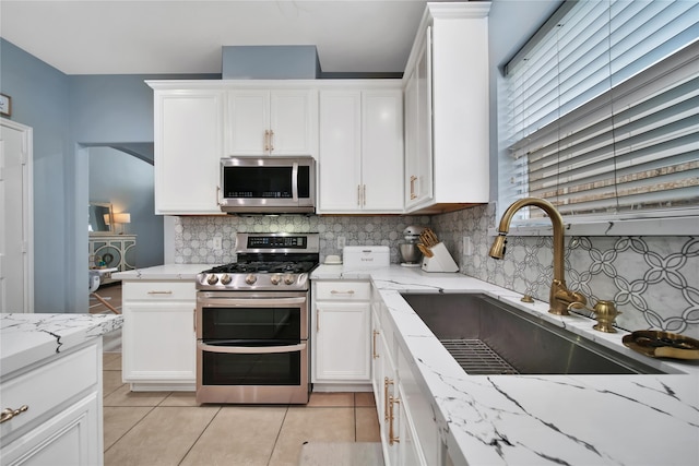 kitchen with stainless steel appliances, sink, tasteful backsplash, and white cabinetry