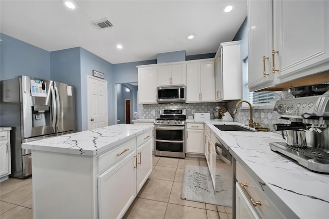 kitchen with appliances with stainless steel finishes, a kitchen island, sink, and white cabinetry