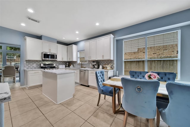 kitchen with a kitchen island, appliances with stainless steel finishes, decorative backsplash, and white cabinetry