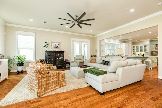 53 Island Psge, Galveston, TX 77554 - living area with crown molding, a ceiling fan, light wood-style floors, and a healthy amount of sunlight