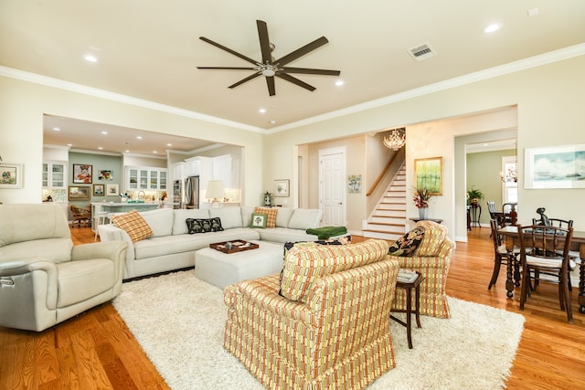 living room with ceiling fan, ornamental molding, and light hardwood / wood-style floors