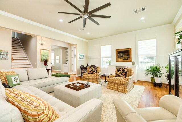 living room with light hardwood / wood-style floors, ceiling fan, and crown molding