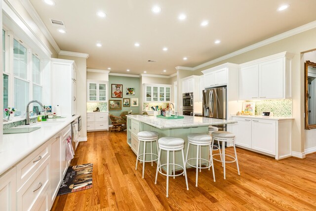 kitchen featuring light hardwood / wood-style floors, sink, white cabinetry, a kitchen island, and stainless steel appliances