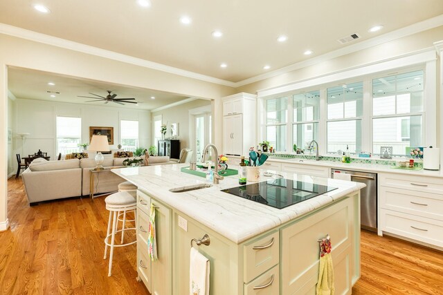 kitchen with an island with sink, white cabinets, light hardwood / wood-style flooring, ceiling fan, and stainless steel dishwasher