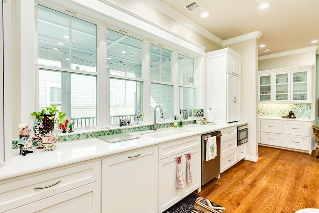 kitchen featuring sink, light hardwood / wood-style flooring, backsplash, stainless steel appliances, and crown molding