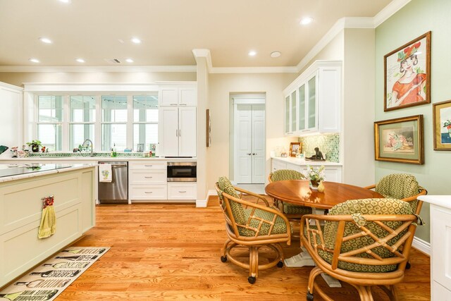 kitchen with light wood-type flooring, backsplash, appliances with stainless steel finishes, and white cabinets